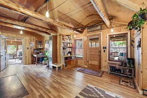Foyer entrance with light wood-style floors, beamed ceiling, and wood walls