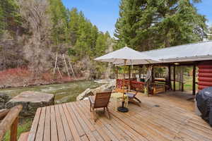 Wooden deck with a water view, area for grilling, a lawn, and view of wooded area