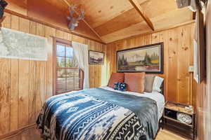 Bedroom featuring wood finished floors, wood walls, and a vaulted wooden ceiling