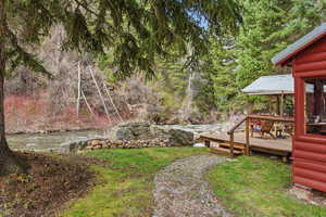 View of yard featuring a deck with water view, a sunroom, and view of scattered trees