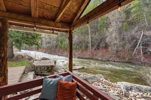 Wooden terrace featuring a water view and a wooded view