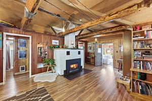 Living room with wood walls, wood finished floors, beam ceiling, and a tile fireplace