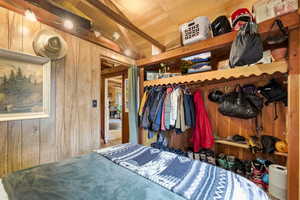 Bedroom featuring wooden walls, vaulted ceiling with beams, and wood ceiling