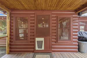 View of exterior entry with heating unit and faux log siding