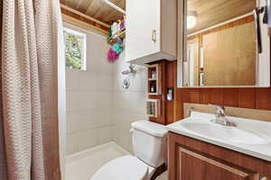 Full bath featuring wooden walls, vanity, a stall shower, and wooden ceiling