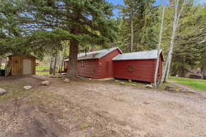 View of property exterior with a storage unit, a metal roof, and log veneer siding