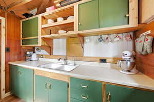 Dual tone kitchen with light countertops, two tone color scheme, open shelves, and wood walls