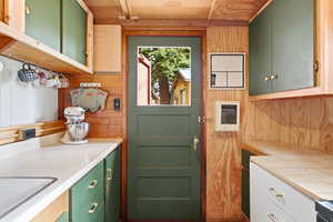 Dual tone kitchen with heating unit, two tone color scheme, tile countertops, and wood walls