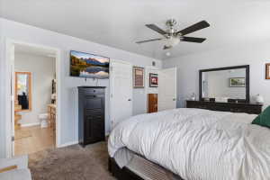Tiled bedroom with carpet floors, ensuite bathroom, and a ceiling fan