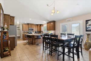 Dining space with vaulted ceiling, hanging lights, and light tile patterned floors