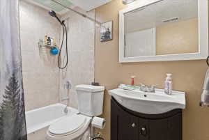 Full bath featuring vanity, shower / tub combo, and a textured wall