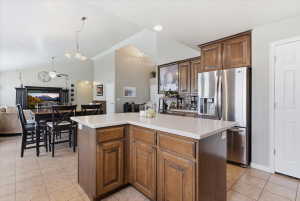 Kitchen featuring stainless steel refrigerator with ice dispenser, open floor plan, light countertops, a kitchen island, and light tile patterned floors