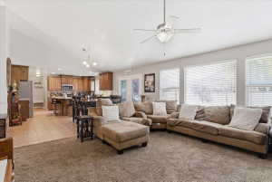 Living area featuring lofted ceiling, a ceiling fan, light colored carpet, light tile patterned flooring, and suspended lighting
