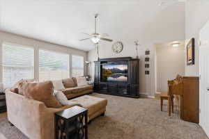 Living room with vaulted ceiling, a ceiling fan, and carpet