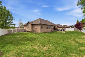 Rear view of house with a fenced backyard and stucco siding