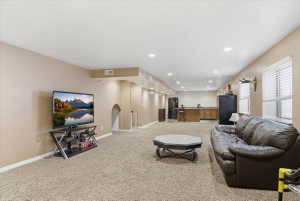 Living room with light carpet, recessed lighting, and arched walkways