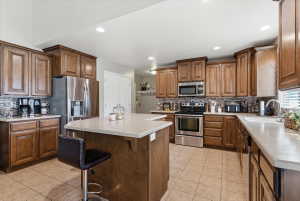 Kitchen with a kitchen bar, stainless steel appliances, backsplash, light tile patterned flooring, and recessed lighting