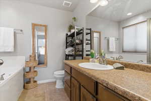 Full bath with a garden tub, vanity, light tile patterned floors, and recessed lighting