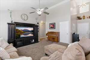 Carpeted living area featuring suspended lighting, lofted ceiling, and ceiling fan