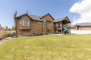 Rear view of property featuring a balcony and a playground