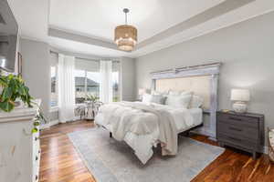 Bedroom featuring a tray ceiling and wood-type flooring