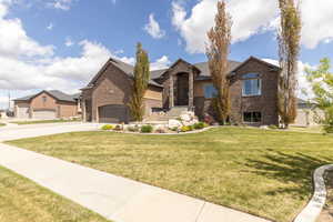 View of front of home with brick siding, a front lawn, and concrete driveway