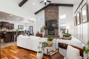 Living area with ceiling fan, a stone fireplace, a chandelier, and light wood finished floors