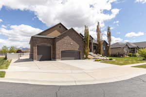 View of front of property with an attached garage, brick siding, and driveway