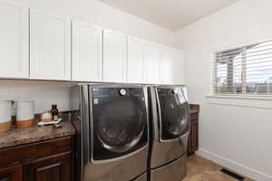 Laundry room featuring washing machine and clothes dryer, light tile patterned floors, and cabinet space
