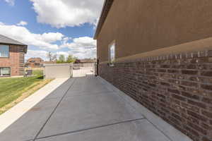 View of home's exterior featuring a gate, brick siding, a patio, and a residential view