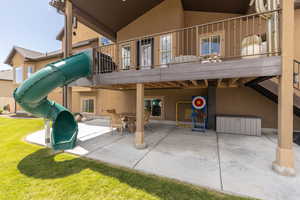 Rear view of property with outdoor dining area, stucco siding, a balcony, a yard, and a patio area