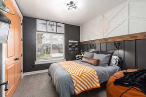 Carpeted bedroom with baseboards and an accent wall