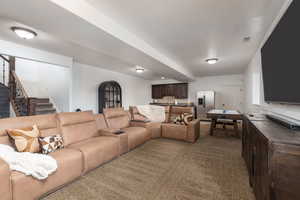 Living area with stairs and dark carpet