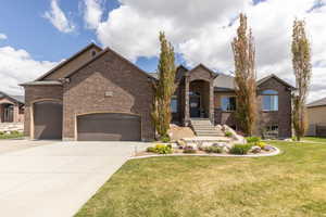 View of front of home with brick siding, a front yard, a garage, and concrete driveway