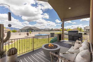 Wooden terrace featuring grilling area, a fire pit, a fenced backyard, and a residential view