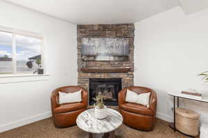 Sitting room featuring a stone fireplace and carpet floors