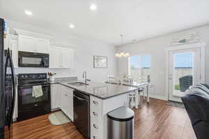 Kitchen featuring a peninsula, black appliances, white cabinets, and dark stone countertops
