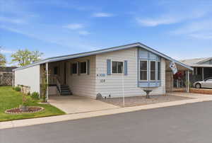 View of front of house with a carport, concrete driveway, entry steps, and a front yard