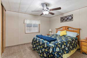 Bedroom featuring carpet floors, ceiling fan, and a decorative wall