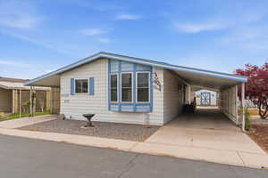 Manufactured / mobile home featuring a carport, concrete driveway, and a storage unit