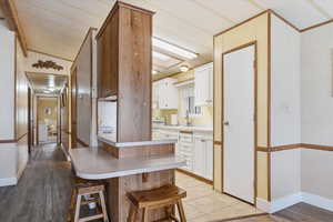 Kitchen with light countertops, white cabinetry, white stove, a breakfast bar, and light wood-type flooring