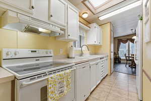 Kitchen featuring white appliances, light countertops, and white cabinetry
