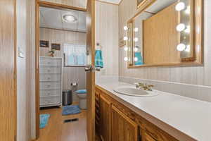 Bathroom featuring wallpapered walls, vanity, light wood-type flooring, and a textured ceiling