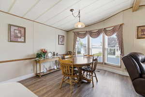 Dining space with wood finished floors and vaulted ceiling