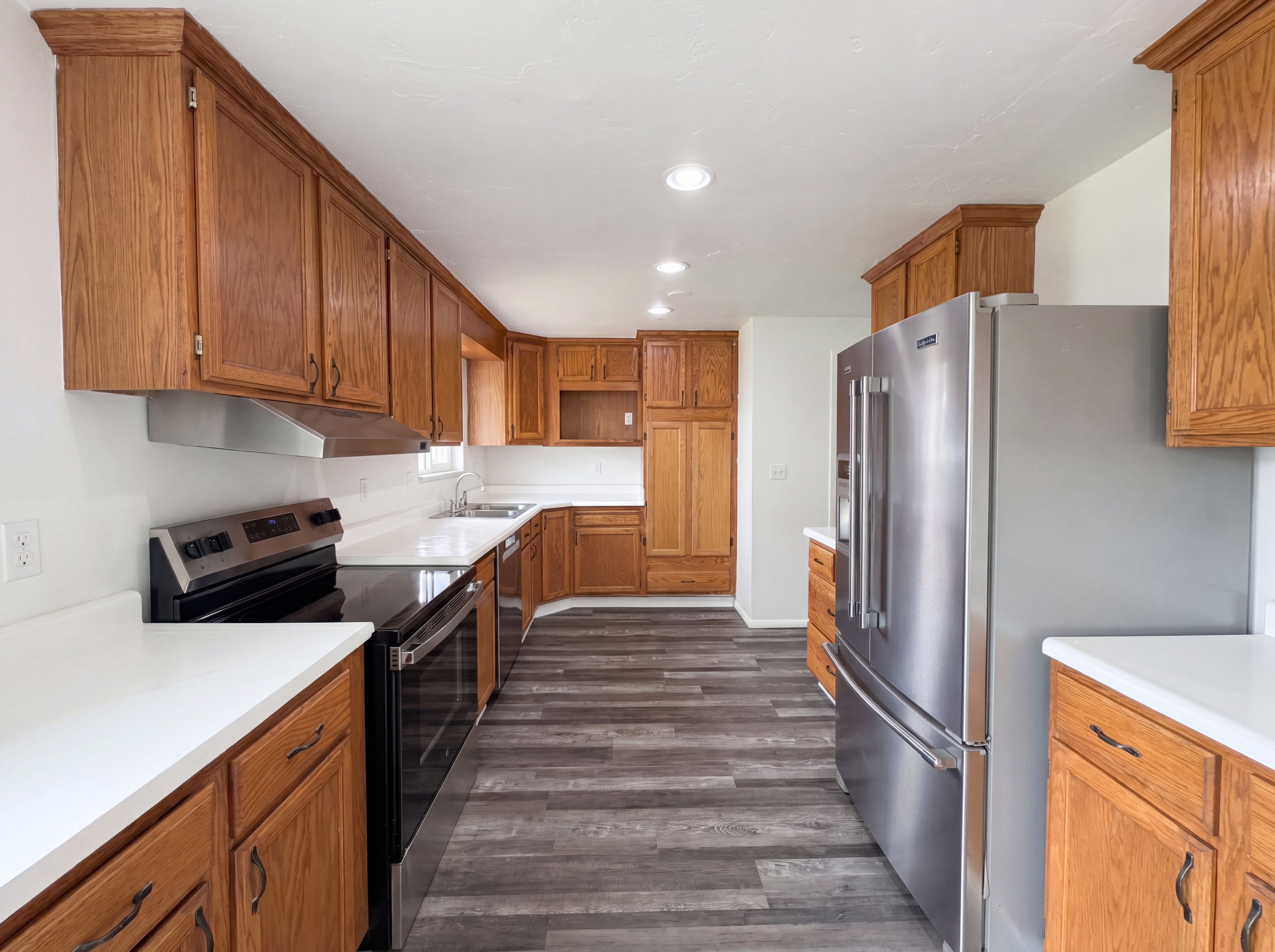 Kitchen featuring stainless steel appliances, light countertops, wood finish cabinets, and recessed lighting