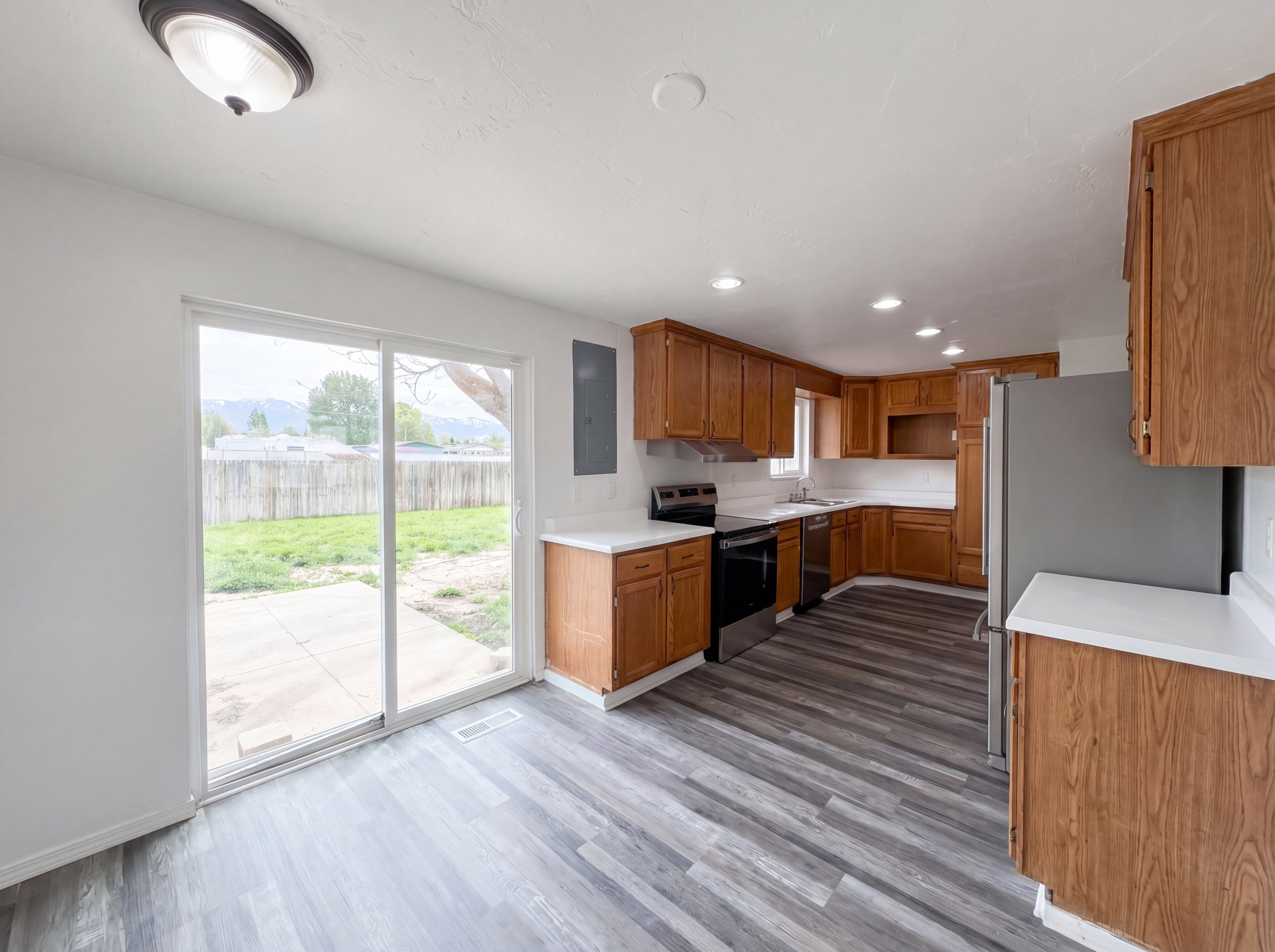 Kitchen featuring wood finish cabinetry, light countertops, stainless steel appliances, recessed lighting, and light wood-style flooring