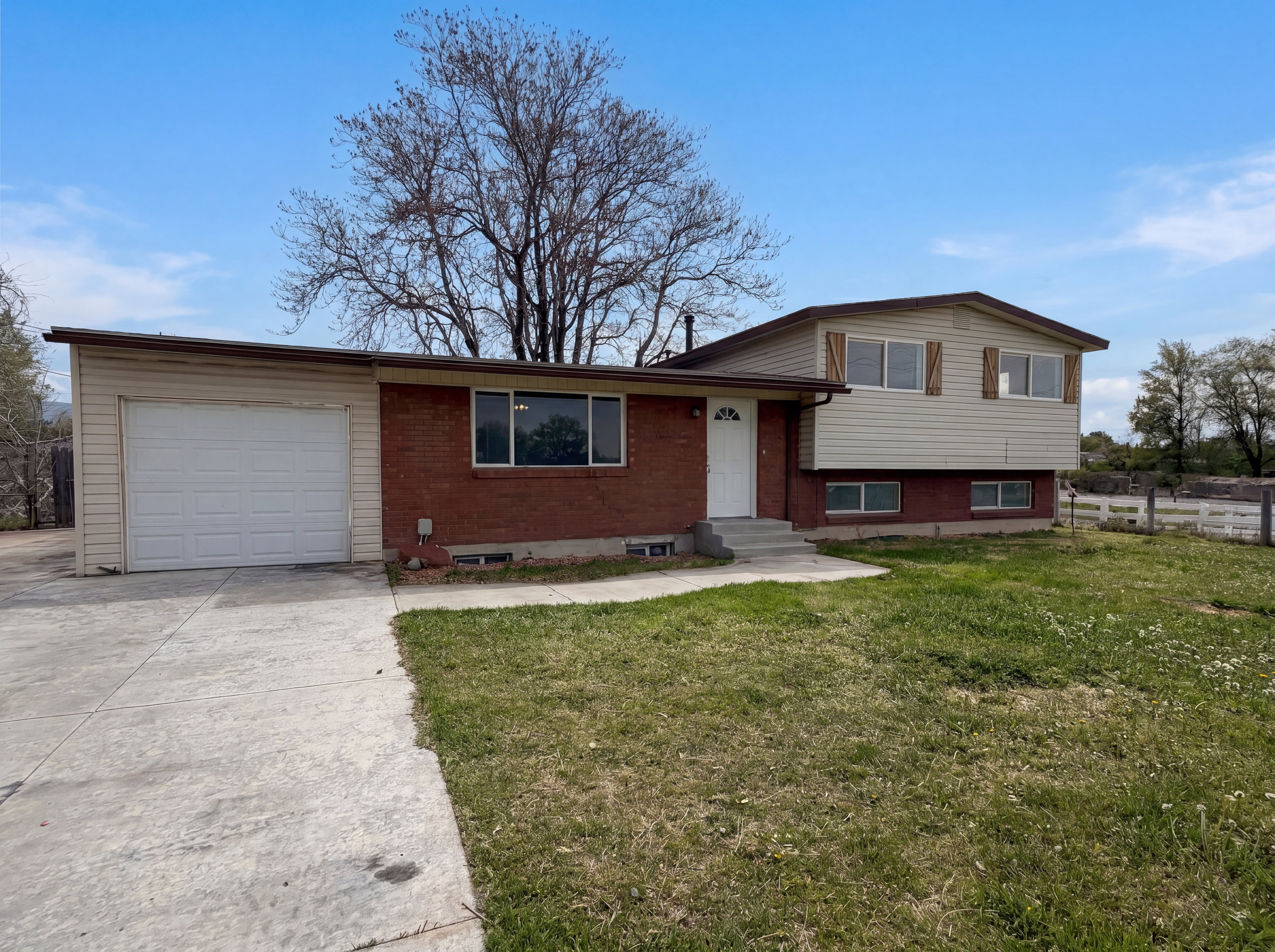 Tri-level home featuring an attached garage, brick siding, and driveway