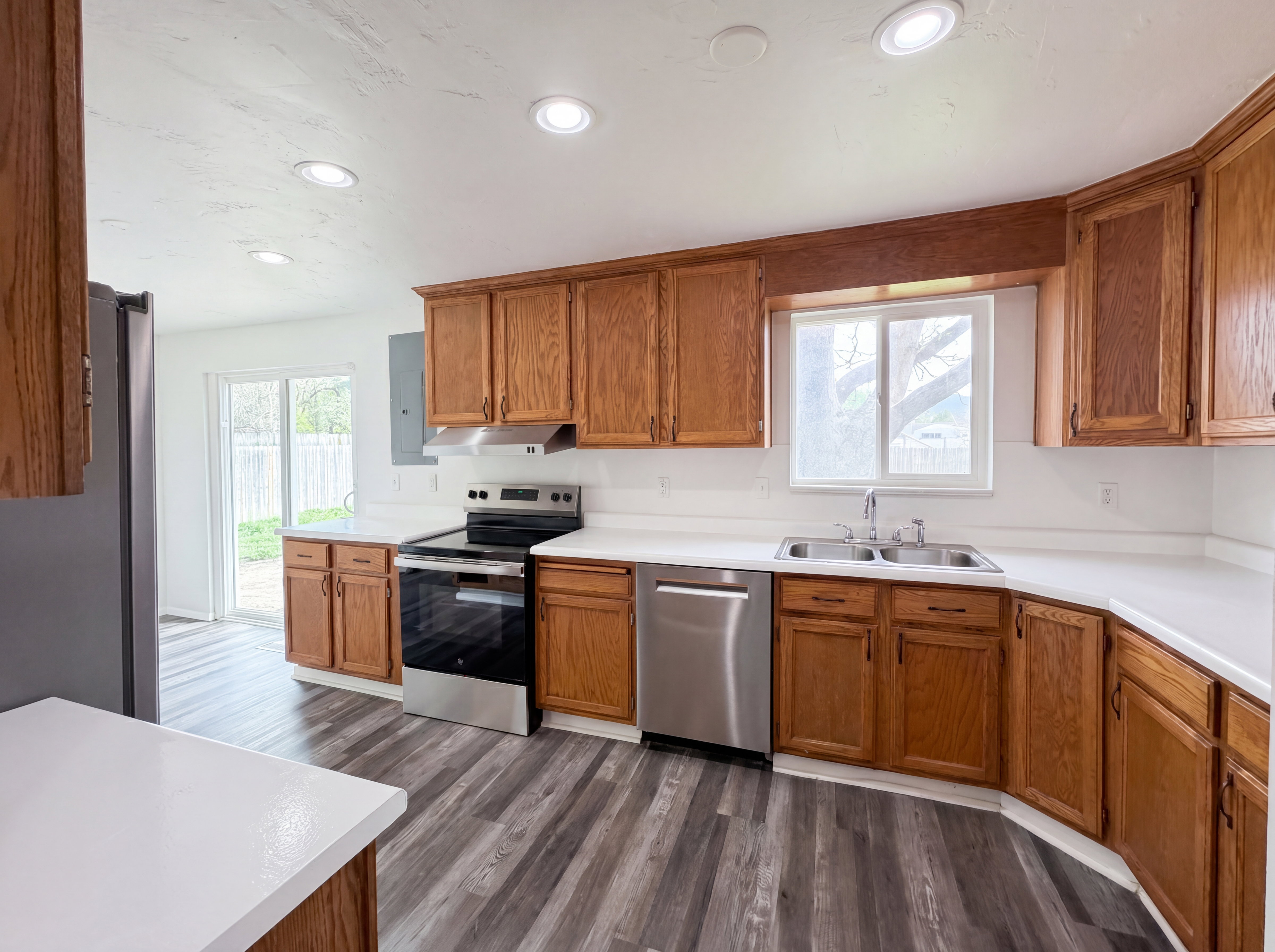 Kitchen with stainless steel appliances, wood finish cabinets, light countertops, and recessed lighting
