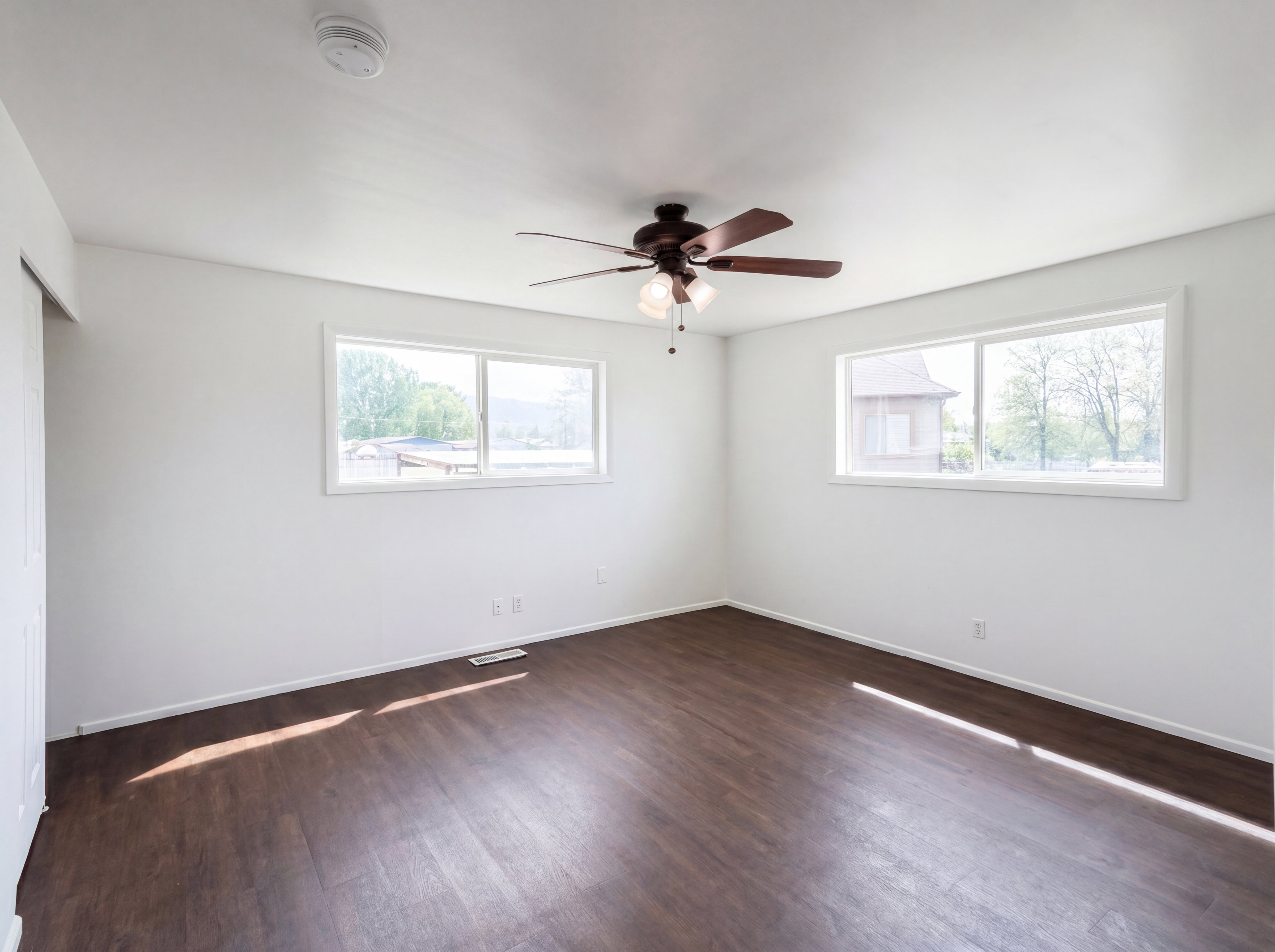 Spare room featuring dark wood-type flooring, a ceiling fan, healthy amount of natural light, and a smoke detector