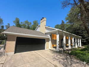 Brick exterior with a prominent two-car garage, a covered front entry supported by white columns, and a visible chimney feature